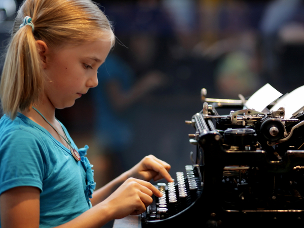 Ein Mädchen tippt auf einer historischen Schreibmaschine