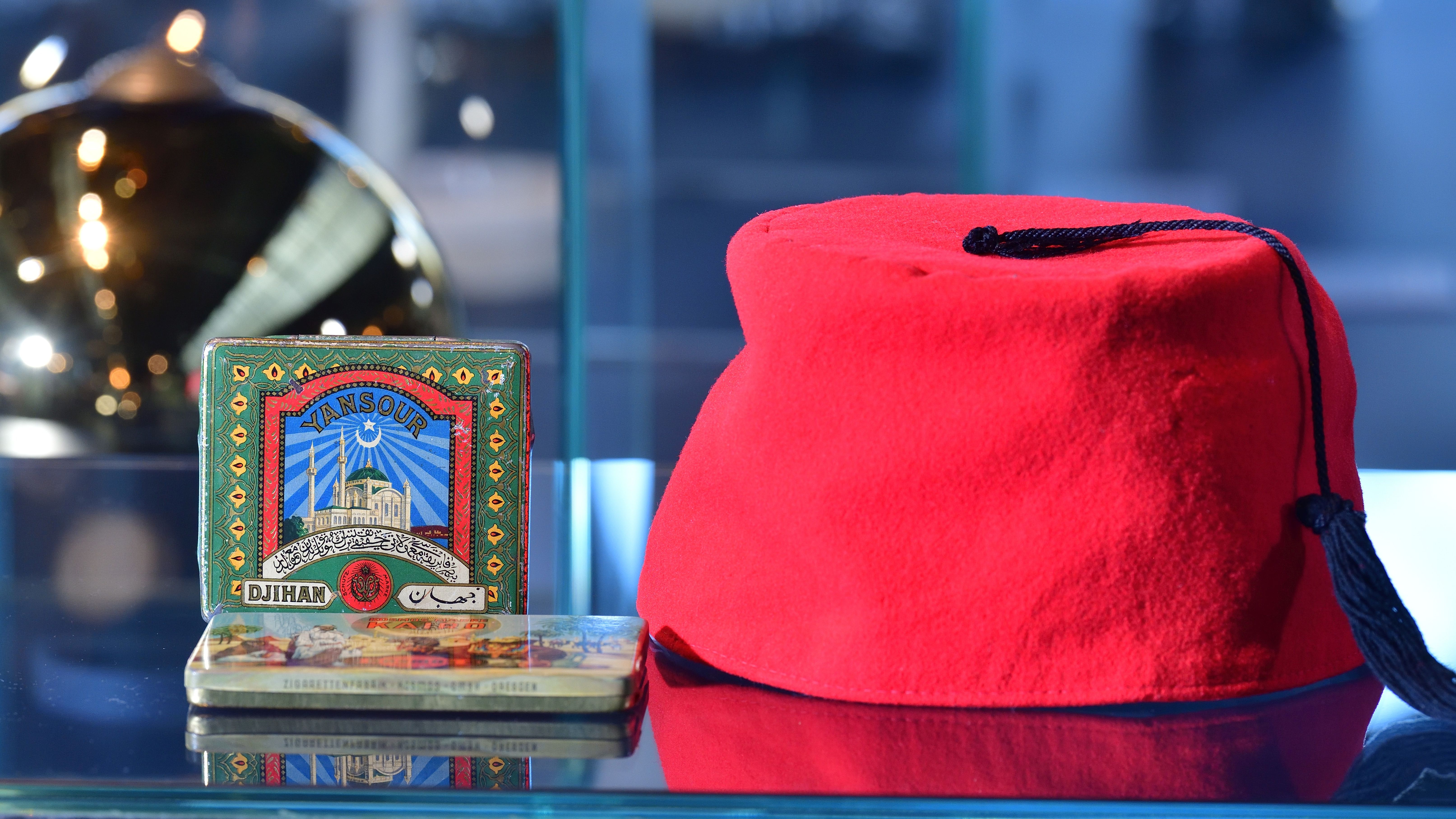 Details der Ausstellung: links: Zigarettenschachteln aus Blech, rechts: Fes (orientalische Kopfbedeckung)